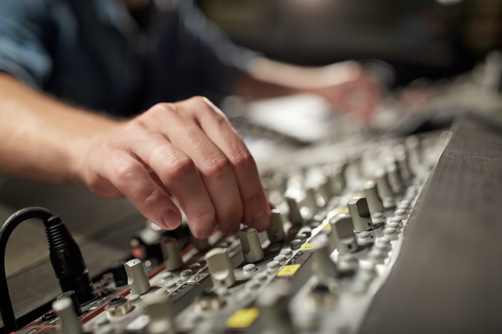 man using mixing console in music recording studio